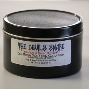 May include: A black metal tin candle with a white label that reads "THE DEVILS SNARE" Misfire & Dread Candles Oak Moss, Oak Wood, Clary Sage Horror Inspired Scents Soy & Vegetable Blended Wax NET WT. 8 OZ 266 (0)"