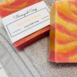 May include: A bar of goat milk soap with a swirl of pink and yellow. The soap is labeled "Farmyard Soap" and "Autumn Vibes".