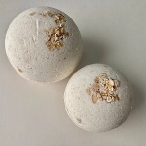 Unscented Oatmeal Bath Bomb. The color is a natural light beige from the oatmeal mixed into the bath bomb. The Oatmeal bath bomb is also topped with whole grain oats. Dye free and fragrance free.  A Six and four ounce round bath bomb size, pictured.