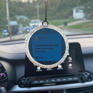 May include: A silver glitter car air freshener with a blue background and the text "Salty & Sweet" and "'Cause I am salty and sweet (ooh-ooh, ooh-ooh)" and a Spotify logo.