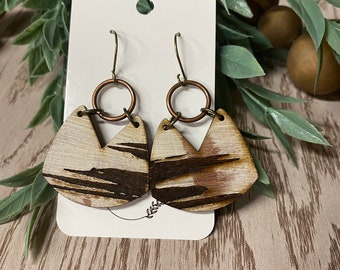 May include: A pair of wooden earrings with a brown and white woodgrain pattern. The earrings are shaped like a teardrop with a small copper ring at the top.