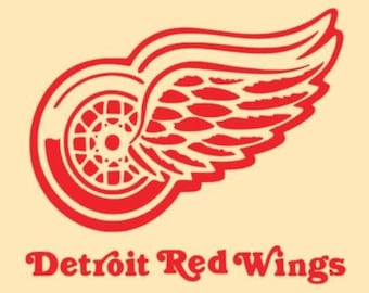Op de afbeelding: Rood en wit logo van het ijshockeyteam Detroit Red Wings. Het logo toont een rode vleugel met een wiel erin. De tekst "Detroit Red Wings" staat onder het logo.