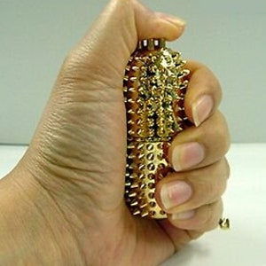 May include: A gold-coloured acupressure tool with a textured surface and a rounded shape. The tool is covered in small, raised points.