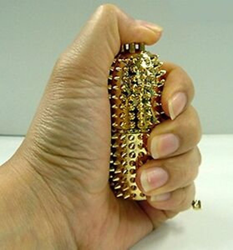 May include: A gold-coloured acupressure tool with a textured surface and a rounded shape. The tool is covered in small, raised points.