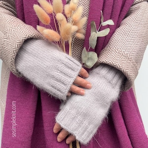 Könnte beinhalten: Ein Paar hellgraue Strickhandschuhe ohne Finger mit geripptem Bündchen, getragen über einem beigen Mantel mit Fischgrätenmuster und einem leuchtend magentafarbenen Schal. Der Text sosimpleknit.com ist links auf dem magentafarbenen Stoff zu sehen.