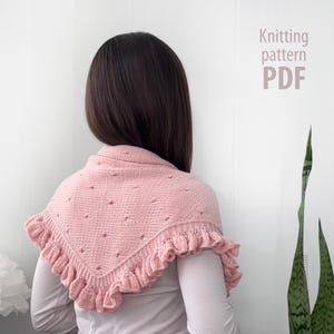 May include: A light pink knitted shawl featuring a textured pattern with small eyelet holes and a ruffled border along the edges. The text Knitting pattern PDF is visible in the upper right corner of the image.