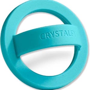 May include: A turquoise-colored, circular object with a band across the center. The band has the word "CRYSTALFY" embossed on it. The object appears to be made of a smooth, possibly rubbery material.