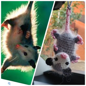May include: A gray and white crocheted opossum hanging from a rearview mirror. The opossum has pink ears and a pink nose.