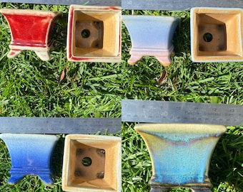 May include: Five different ceramic bonsai pots with various glazes. The pots are all square or rectangular in shape with a raised base and a drainage hole in the bottom. The glazes include red, blue, light blue, and green.