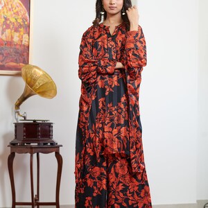 Pu&ograve; includere: Un set di pantaloni palazzo e top a maniche lunghe con stampa floreale nero e arancio. Il top ha un collo a V e una chiusura con bottone. I pantaloni hanno una gamba larga.