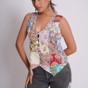 May include: A sleeveless patchwork vest with a V-neckline and button closure. The vest is made of different fabrics with floral and geometric patterns in shades of pink, blue, green, and red.