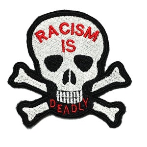 May include: A white skull and crossbones patch with the words "Racism is Deadly" in red embroidered on it.