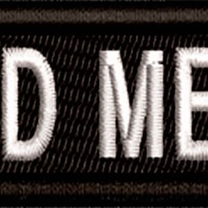 May include: A rectangular black embroidered patch with the words "BOARD MEMBER" in white, block-style letters. The patch has a black border and a textured background.