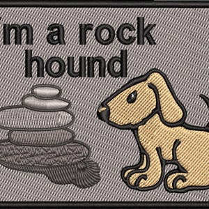 May include: A gray embroidered patch with a cartoon dog and a stack of rocks. The text "I'm a rock hound" is written in black.