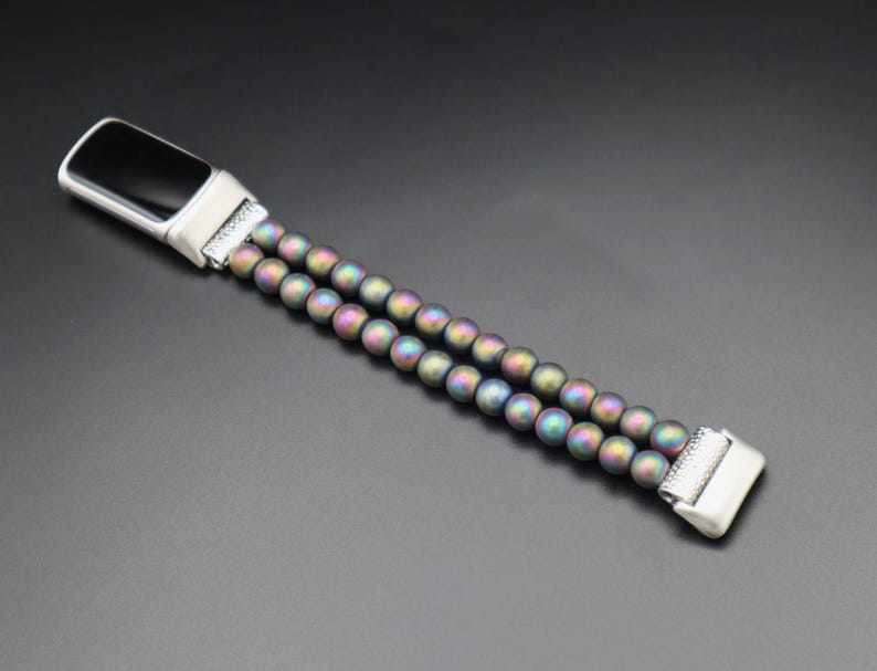 May include: A silver and black fitness tracker with a double-row beaded band. The beads are iridescent and have a rainbow sheen.