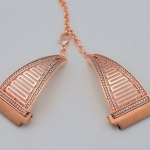 May include: Rose gold watch band with a geometric design and clear crystal accents.