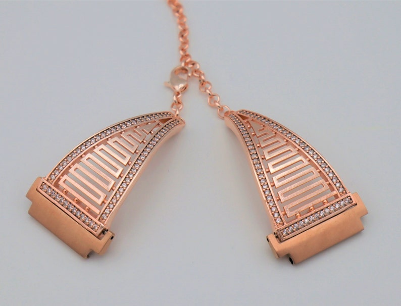 May include: Rose gold watch band with a geometric design and clear crystal accents.