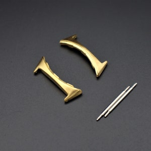 May include: Two gold-colored watch band spring bars and two silver-colored watch band spring bars.