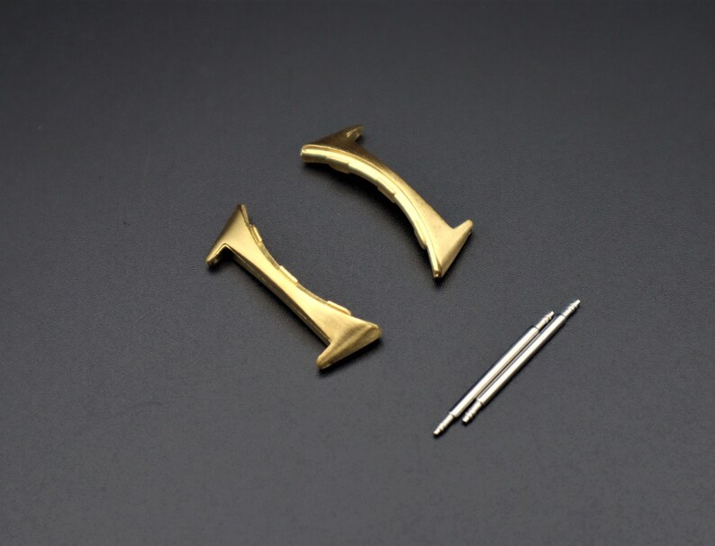 May include: Two gold-colored watch band spring bars and two silver-colored watch band spring bars.