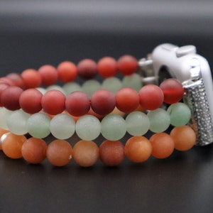 May include: Three layered beaded watch band in shades of red, green, and orange. The band is made of round beads and is designed to fit a smart watch.