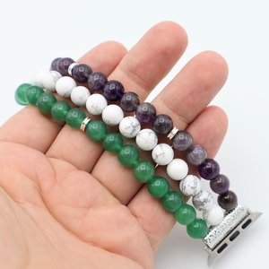 May include: A three-strand beaded Apple Watch band with green, white, and purple beads. The band is made of natural stones and has a silver metal connector.