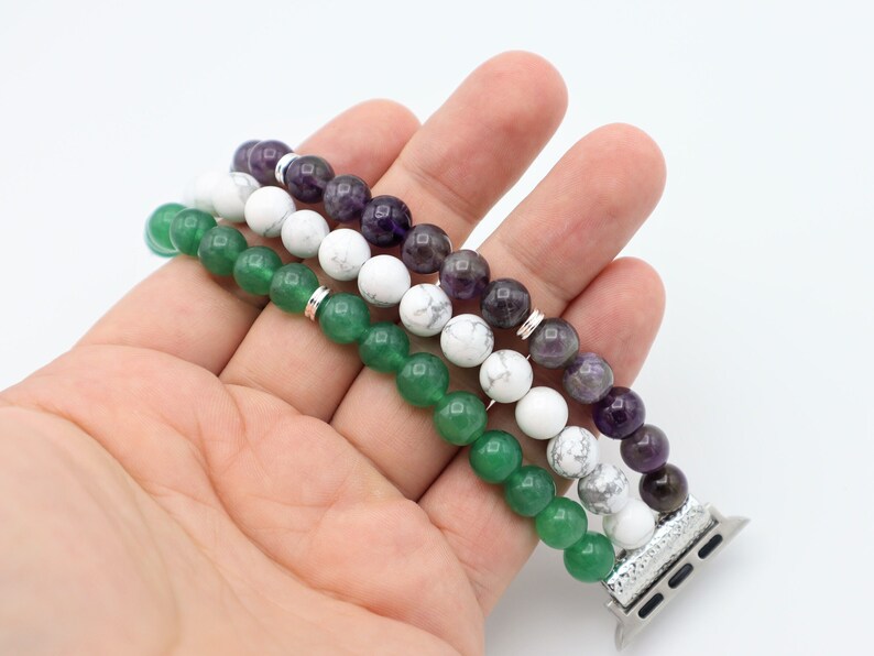 May include: A three-strand beaded Apple Watch band with green, white, and purple beads. The band is made of natural stones and has a silver metal connector.