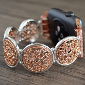 Puede incluir: Una pulsera de reloj de oro rosa y plata con un diseño de filigrana decorativo. La pulsera está compuesta por múltiples piezas circulaires enlazadas.