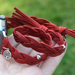 May include: Red braided leather watch band with a silver tree charm and silver beads. The band has a fringe detail.