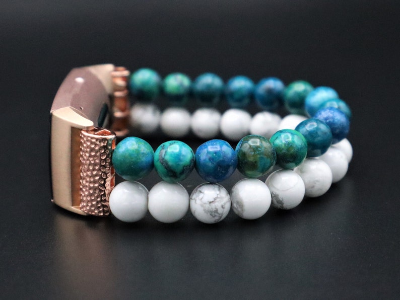 May include: A rose gold smartwatch band with a double row of beads. The top row is blue and green, and the bottom row is white.