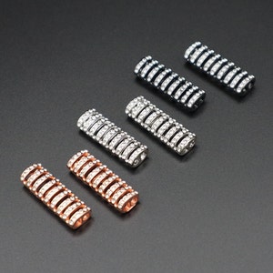 May include: Six metal bar-shaped jewelry connectors with clear rhinestones. The connectors are in different metal finishes: silver, gold, rose gold, and black.