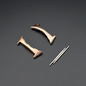 May include: Two gold-toned watch band spring bars and two gold-toned watch band end pieces.