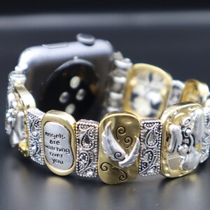 May include: A gold and silver watch band with a charm bracelet style. The charms feature angels, wings, and the text "angels are watching over you".