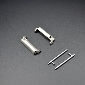 May include: Two silver watch band spring bars and two silver watch band quick release pins.