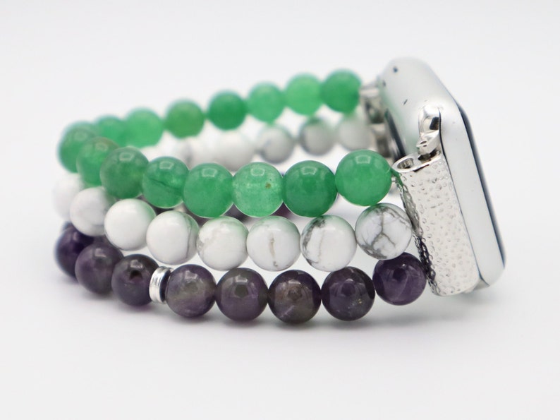 May include: A three-strand beaded Apple Watch band with green, white, and purple beads. The band is made of natural stones and is designed to fit a standard Apple Watch.