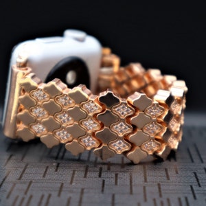 May include: Rose gold Apple Watch band with a diamond-like pattern. The band is made of metal and has a shiny finish.