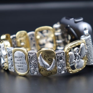 Puede incluir: Pulsera de reloj en tono dorado y plateado con estilo de pulsera de abalorios. Los abalorios presentan alas de ángel, un ángel y el texto "los ángeles te están cuidando".