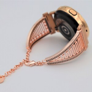 May include: Rose gold watch band with a geometric design and a diamond-like finish. The band is made of metal and has a clasp closure.