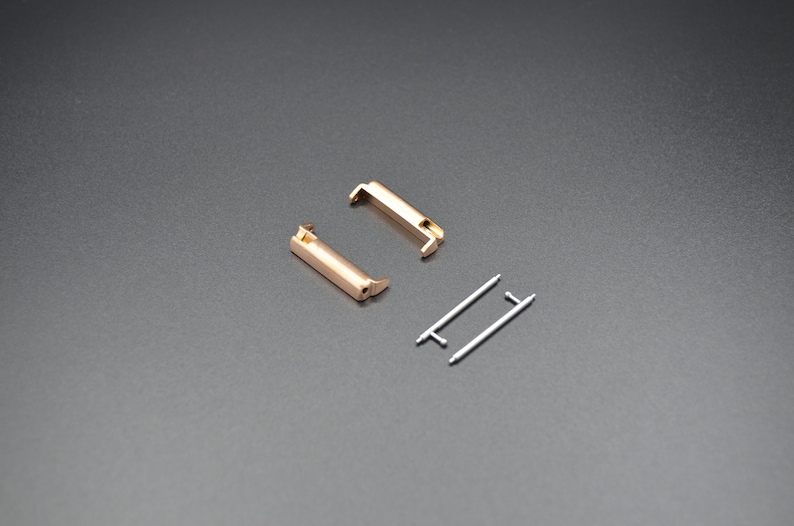May include: Two gold-colored metal watch band connectors and two silver-colored metal spring bars.