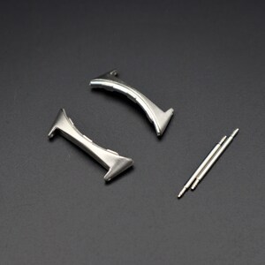 May include: Two silver watch band spring bars and two silver watch band clasps.