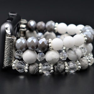 May include: A silver and white beaded watch band with a black watch face. The band is made of multiple strands of beads, including white, gray, and clear beads.