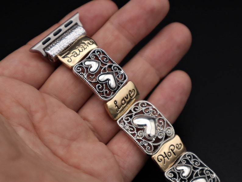 May include: A silver and gold watch band with a decorative design featuring hearts and the words "Faith", "Love", and "Hope".