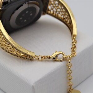 May include: Gold-tone watch band with a delicate, intricate design. The band is made of metal and has a chain-link closure.