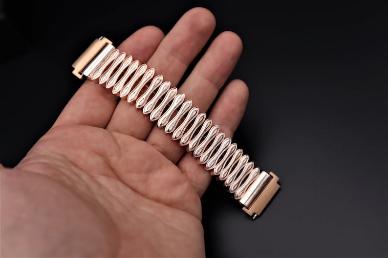 K&ouml;nnte beinhalten: Ein ros&eacute;goldenes Armband mit einem einzigartigen, strukturierten Design. Das Armband ist aus Metall und hat eine polierte Oberfl&auml;che.