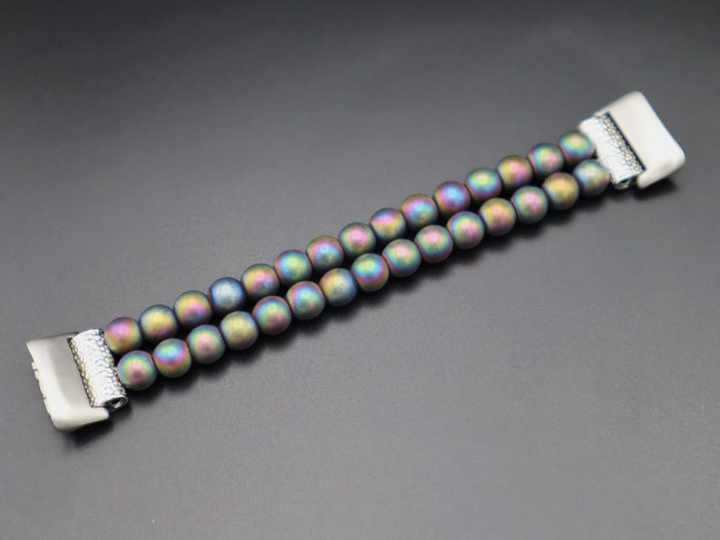 May include: A double-row bracelet made of iridescent, dark grey beads with silver metal clasps.