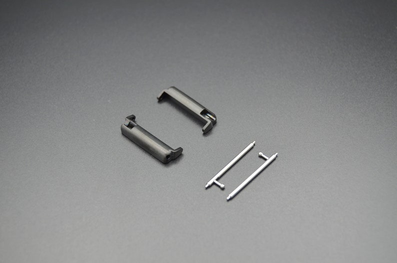 May include: Two black metal watch band spring bars and two silver metal watch band spring bars.