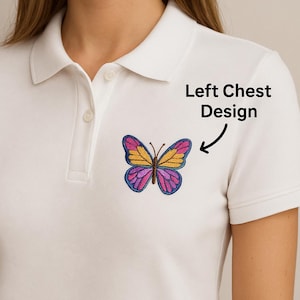 May include: White polo shirt with a colorful butterfly design embroidered on the left chest. The butterfly features yellow, purple, and blue wings. The text "Left Chest Design" is also visible.