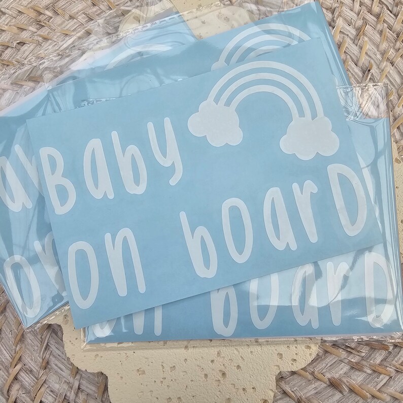 May include: Three blue vinyl decals with white text and a rainbow design. The text reads "Baby on board".