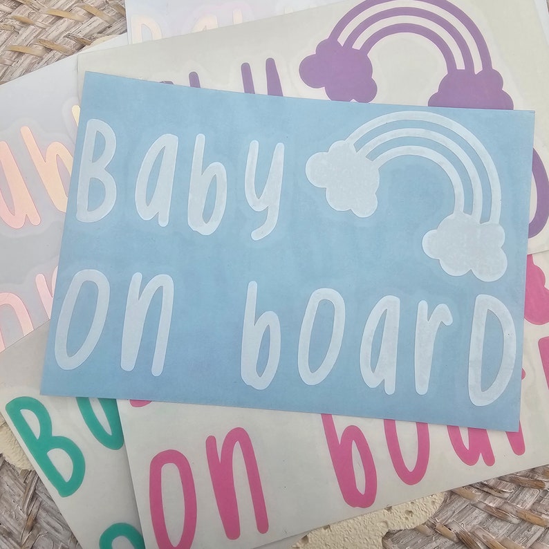 May include: A set of five car decals with a rainbow and the text "Baby on board" in white lettering. The decals are on a light blue, pink, green, and purple background.