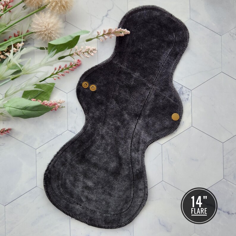 May include: A dark gray reusable cloth menstrual pad with snaps. The pad is 14 inches long and is labeled "14" Flare".