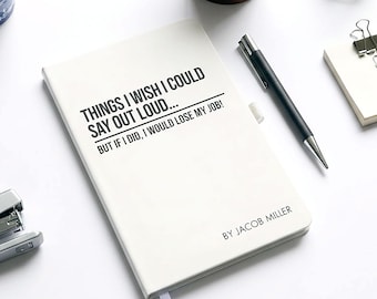 May include: A white notebook with the text "THINGS I WISH I COULD SAY OUT LOUD... BUT IF I DID, I WOULD LOSE MY JOB!" and "BY JACOB MILLER". A black pen, stapler, and other office supplies are on a white surface.